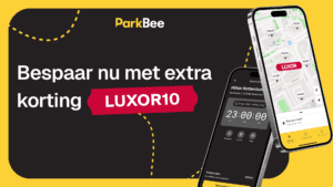 Promotiebanner van ParkBee met de tekst 'Bespaar nu met extra korting LUXOR10'. Op de achtergrond staan twee smartphones met de ParkBee-app en een kaart van Rotterdam bij het Luxor Theater.